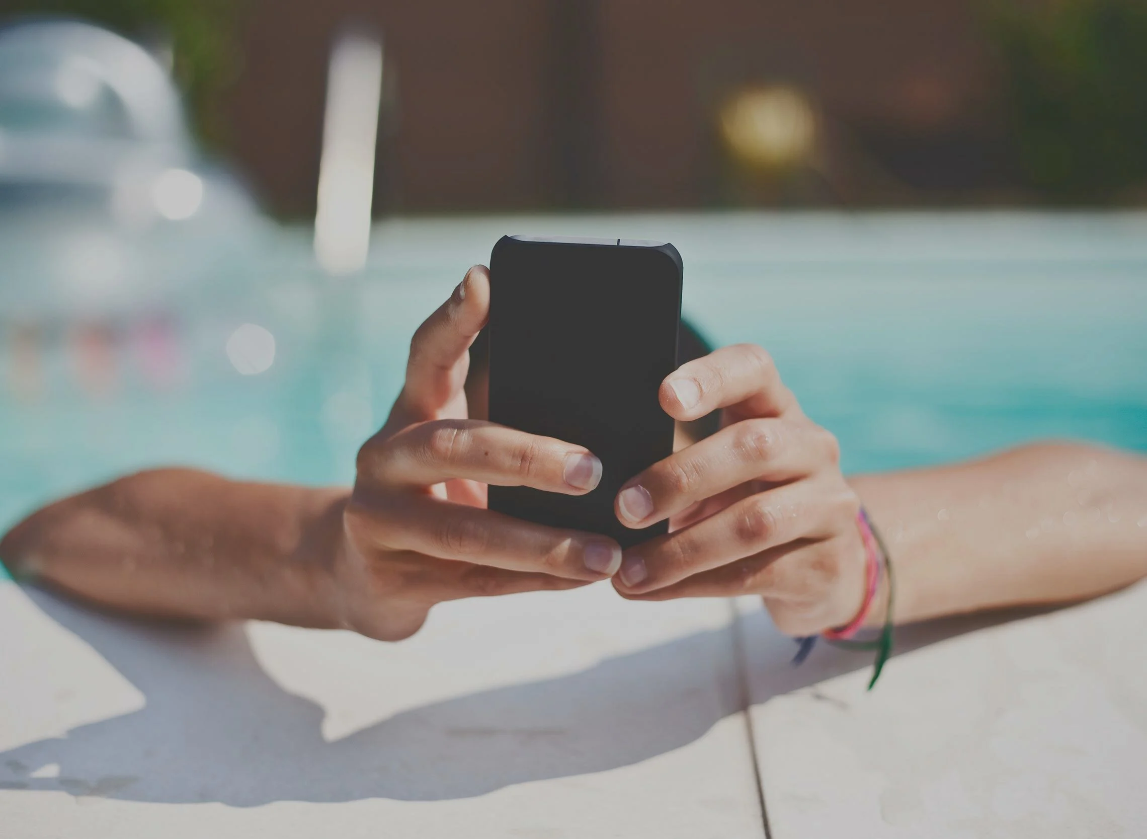 Hands holding a phone by the pool